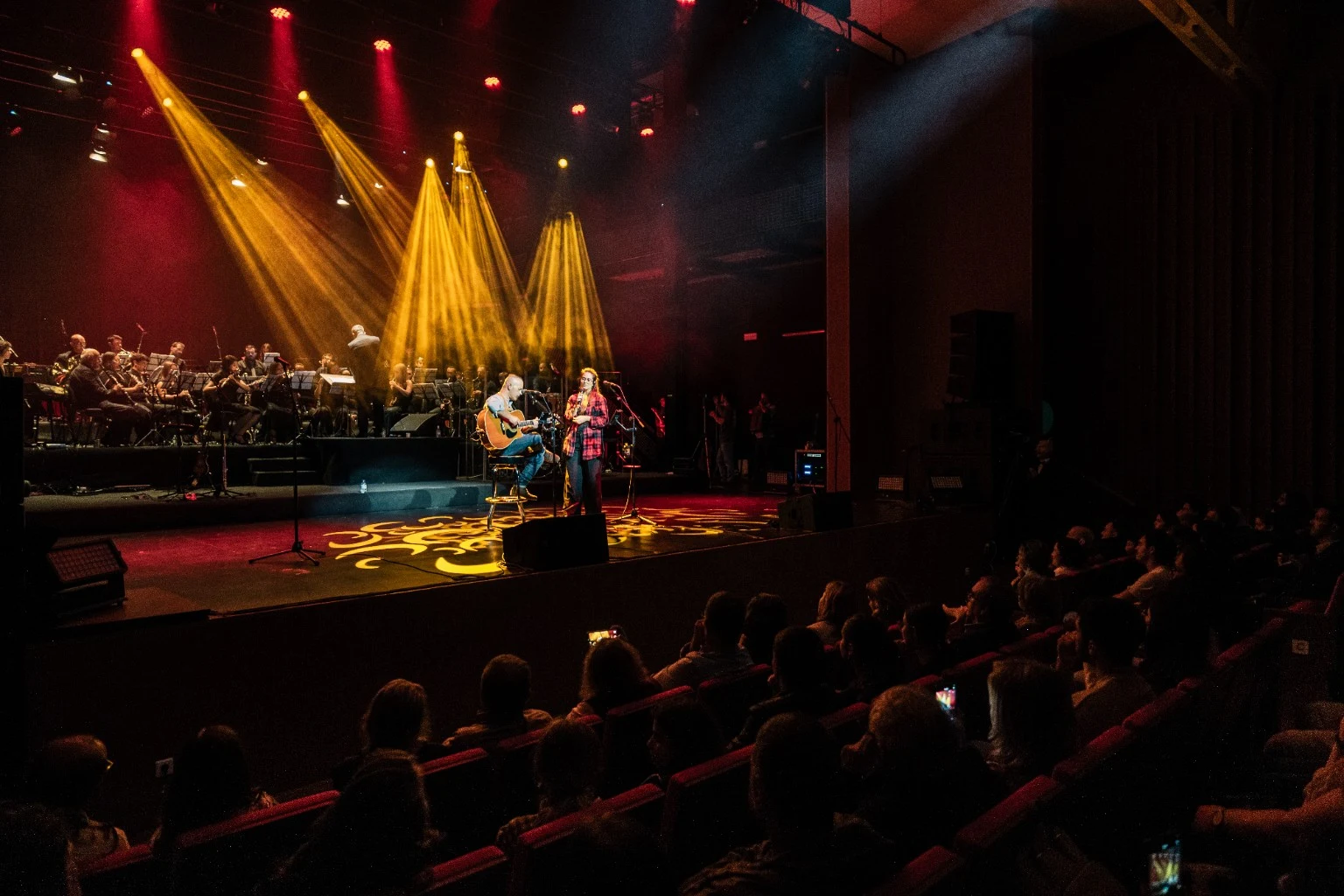 Música, luz e público numa vista da sala.